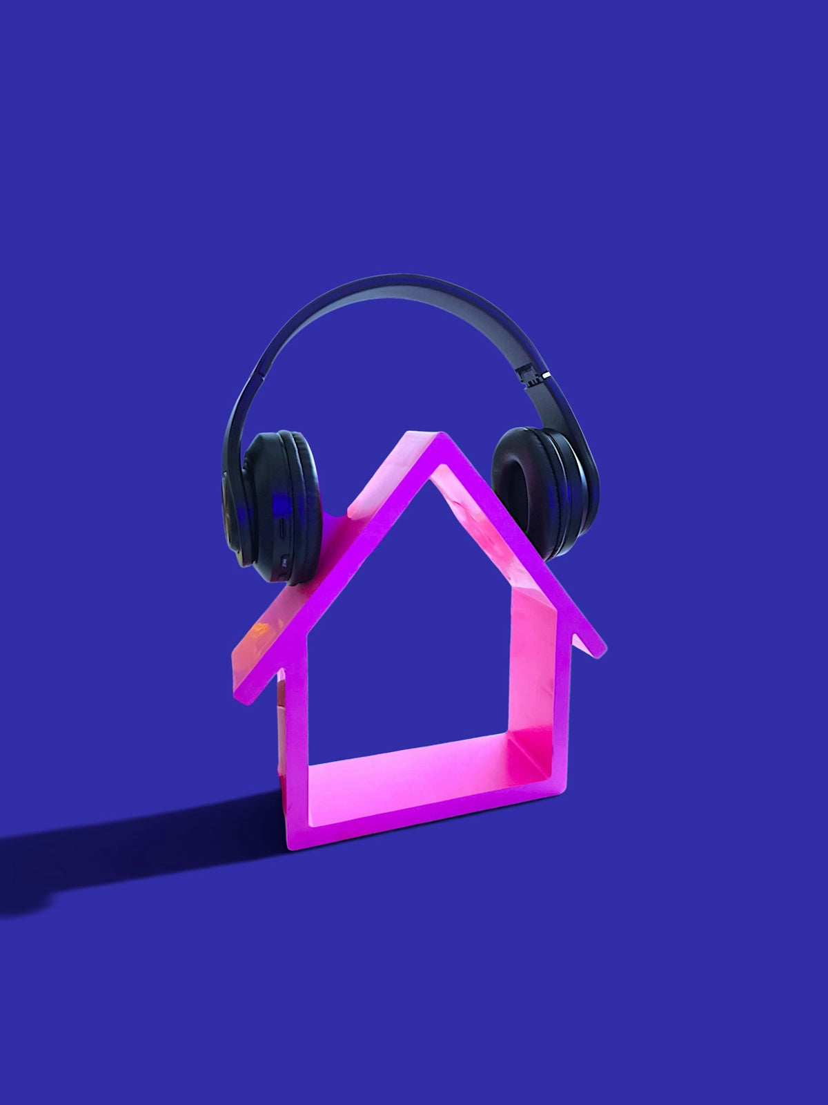 Pink house outline with black headphones on blue background